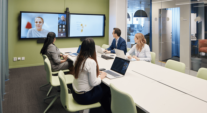 Four co-workers sitting around a conference table during a virtual meeting.